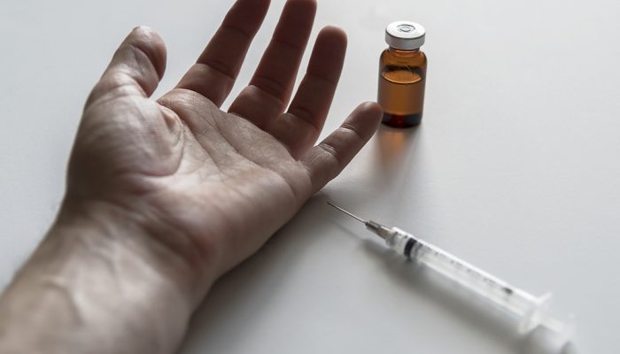 Human arm with vial of drug with syringe in color