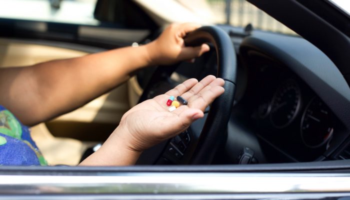Women taking pills inside her car while driving